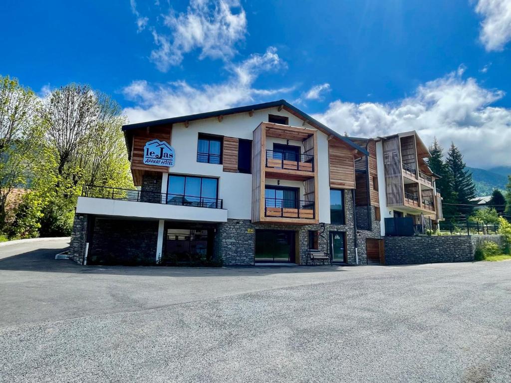 un grand bâtiment sur le côté d'une route dans l'établissement Appart Hôtel Le JAS, à Ancelle