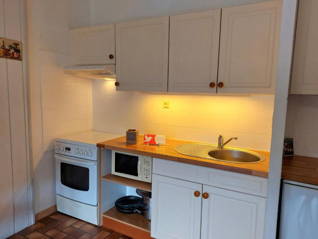 une cuisine avec des armoires blanches et un évier dans l'établissement Apartment Les G'rets-7 by Interhome, à Saint-Gervais-les-Bains