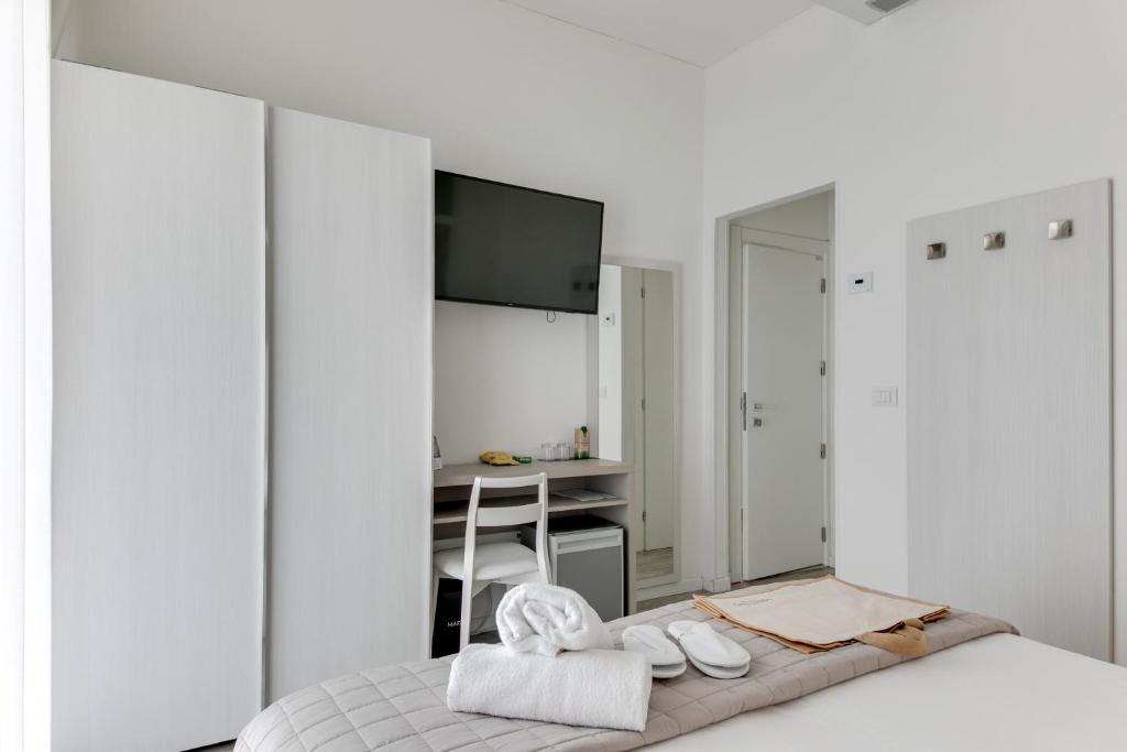 une chambre blanche avec un lit et un bureau dans l'établissement MARITTIMO Milano Marittima, à Milano Marittima