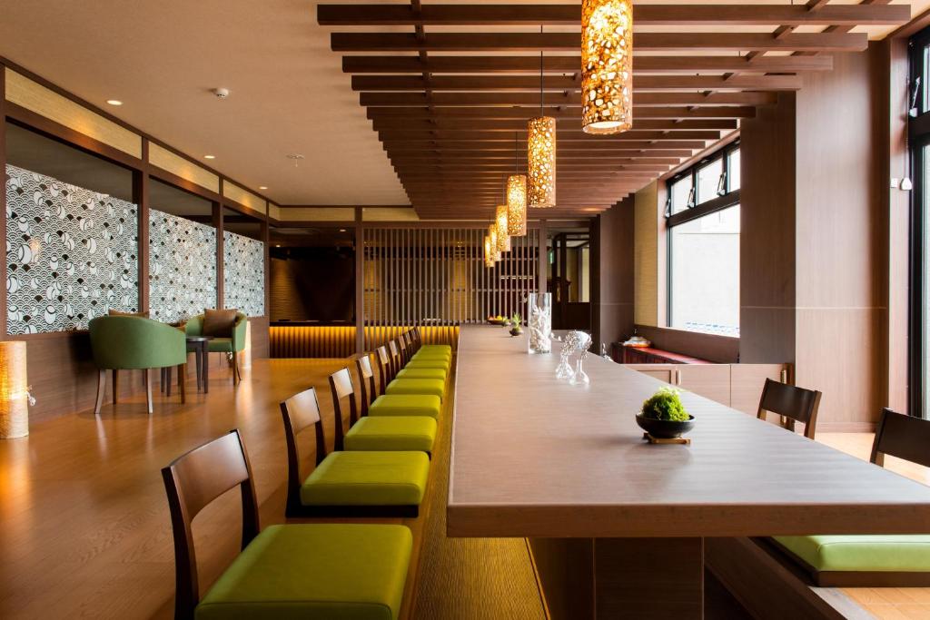 une salle à manger avec une grande table et des chaises vertes dans l'établissement Umiusagi, à Higashiizu