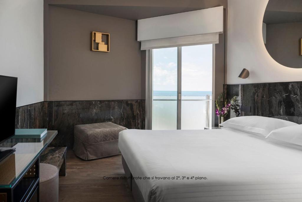une chambre avec un lit et une grande fenêtre dans l'établissement Hotel Michelangelo, à Riccione