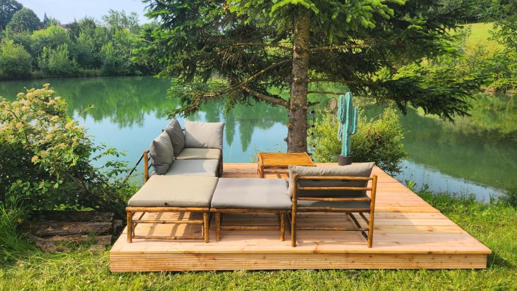 un quai en bois avec un canapé et des chaises sur un lac dans l'établissement tipi des sioux, à Moulayrès