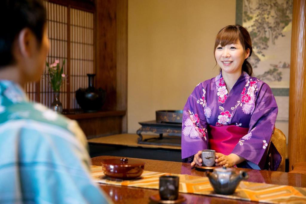une femme assise à une table et parlant à un homme dans l'établissement Ryokan Wataya, à Karatsu