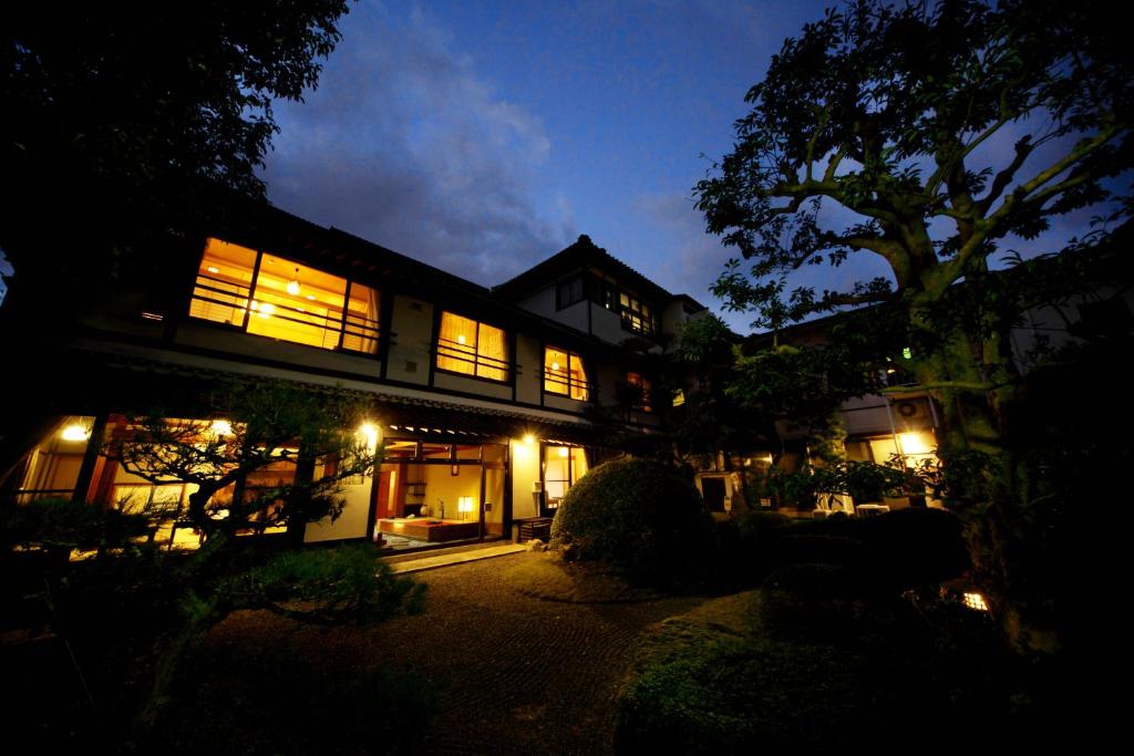 - une maison éclairée la nuit avec des lumières dans l'établissement Ryokan Wataya, à Karatsu