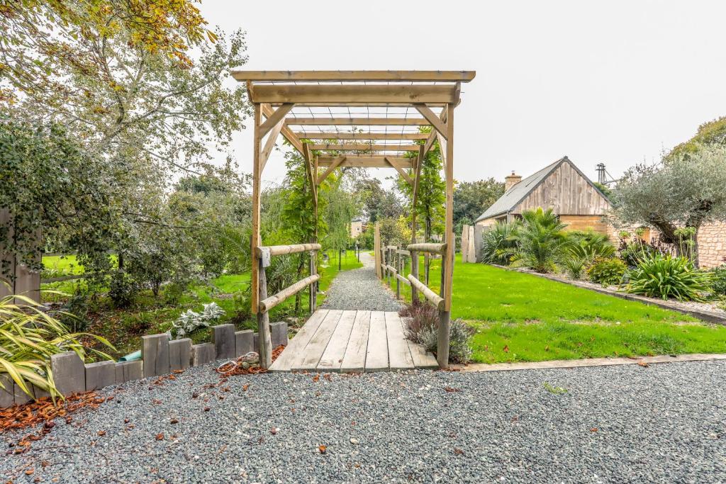 une passerelle en bois dans un jardin avec un belvédère dans l'établissement La Roulotte de la Trigalle, à Valognes 7 autres photos