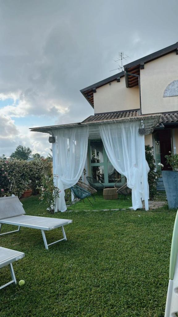 une maison avec des rideaux blancs sur la pelouse dans l'établissement Villa SouAri 10' da Forte de Marmi - 2km spiaggia, à Lido di Camaiore