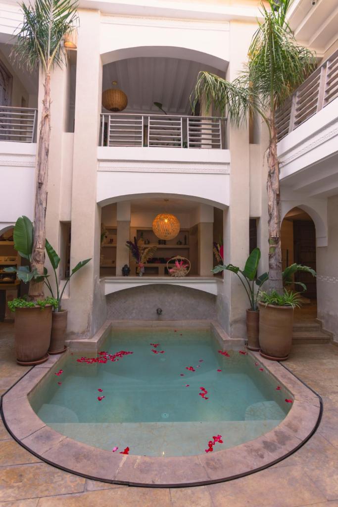 une piscine au milieu d'un immeuble avec des palmiers dans l'établissement Riad Bab Ahmar, à Marrakech