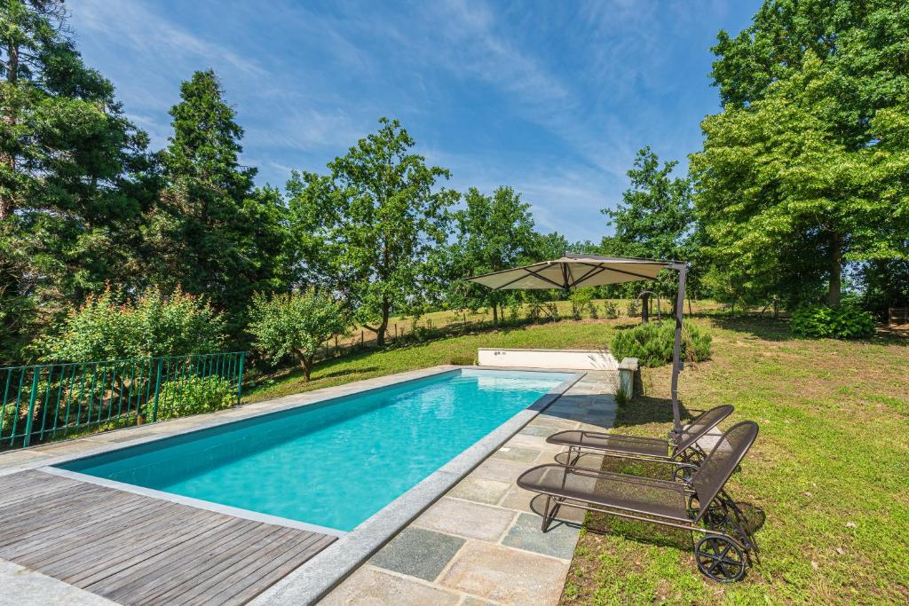 une piscine avec deux chaises et un parasol dans l'établissement Casa Rita, Charming House with pool, Asti, à Asti