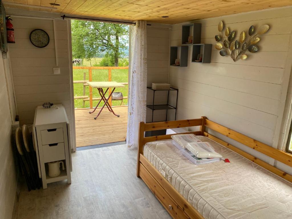 une chambre avec un lit et un porche avec une table dans l'établissement Roulotte dans le Morvan, à Luzy