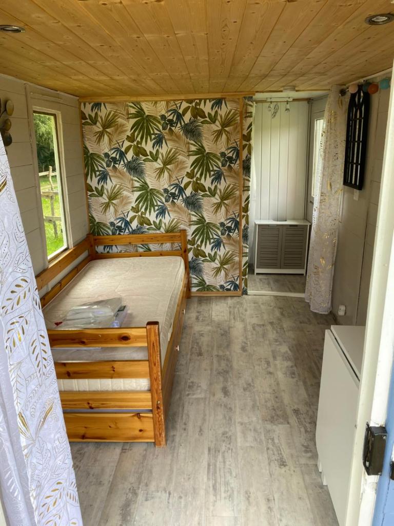 une chambre avec un lit dans une petite pièce dans l'établissement Roulotte dans le Morvan, à Luzy