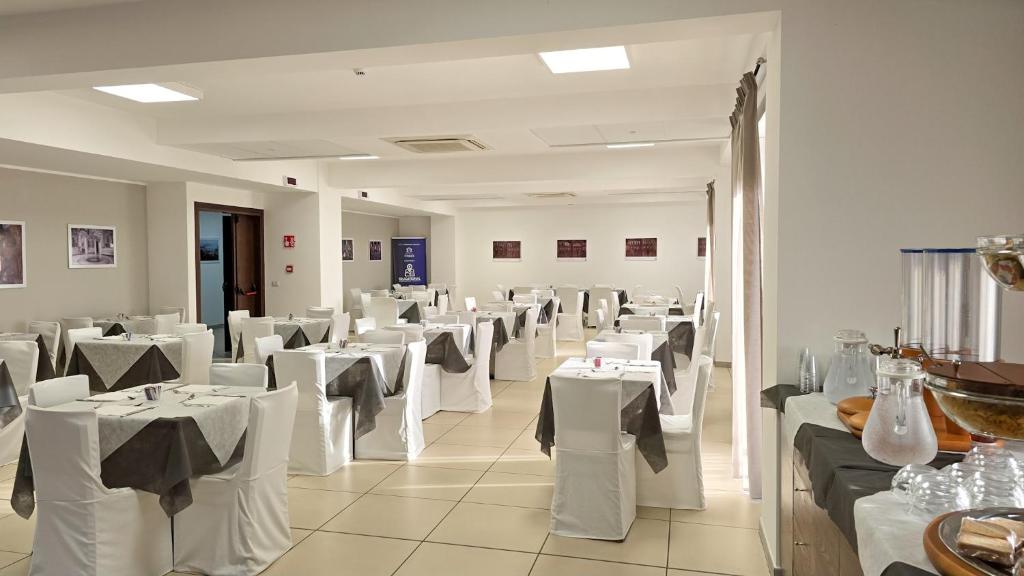une salle à manger avec des tables blanches et des chaises blanches dans l'établissement Aparthotel Codex, à Rossano