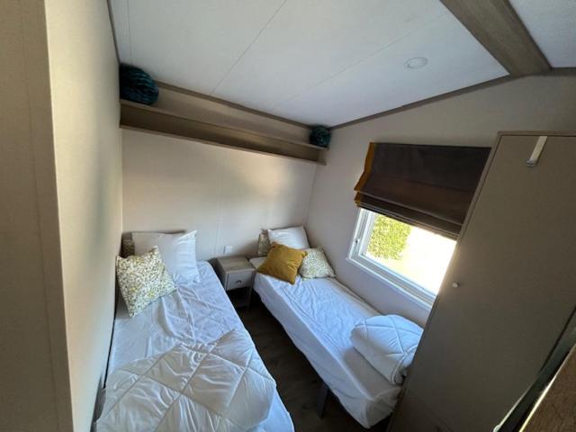une petite chambre avec deux lits et une fenêtre dans l'établissement mobil home climatisé, à Grimaud