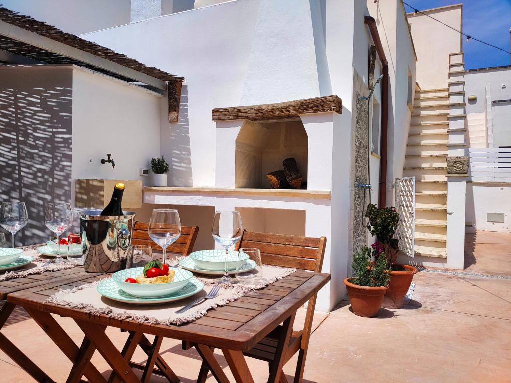 - une table en bois avec des assiettes et des verres à vin sur la terrasse dans l'établissement Da Lorenza di Casa Camilla Journey, à Depressa