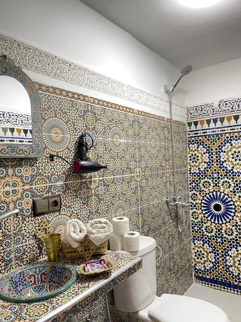 La salle de bains est pourvue de toilettes et d'une douche avec du carrelage. dans l'établissement Riad Blue Oasis, à Fès