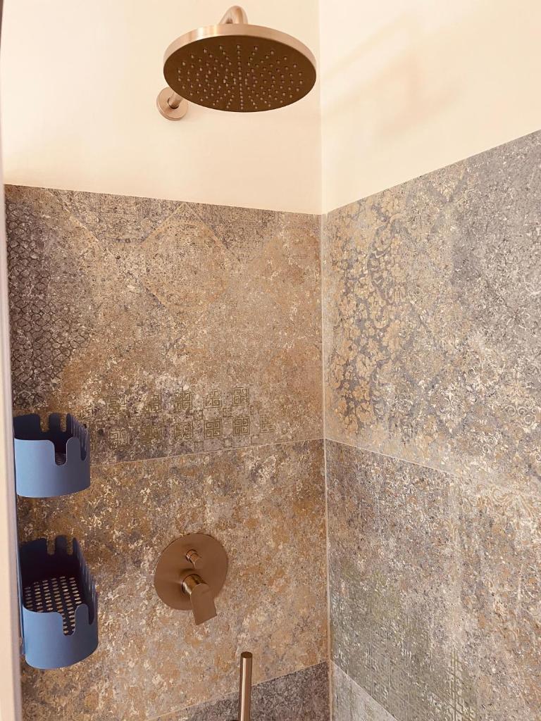 La salle de bains est pourvue d'une douche et d'un mur en pierre. dans l'établissement Villa Case Vecchie, à La Murta