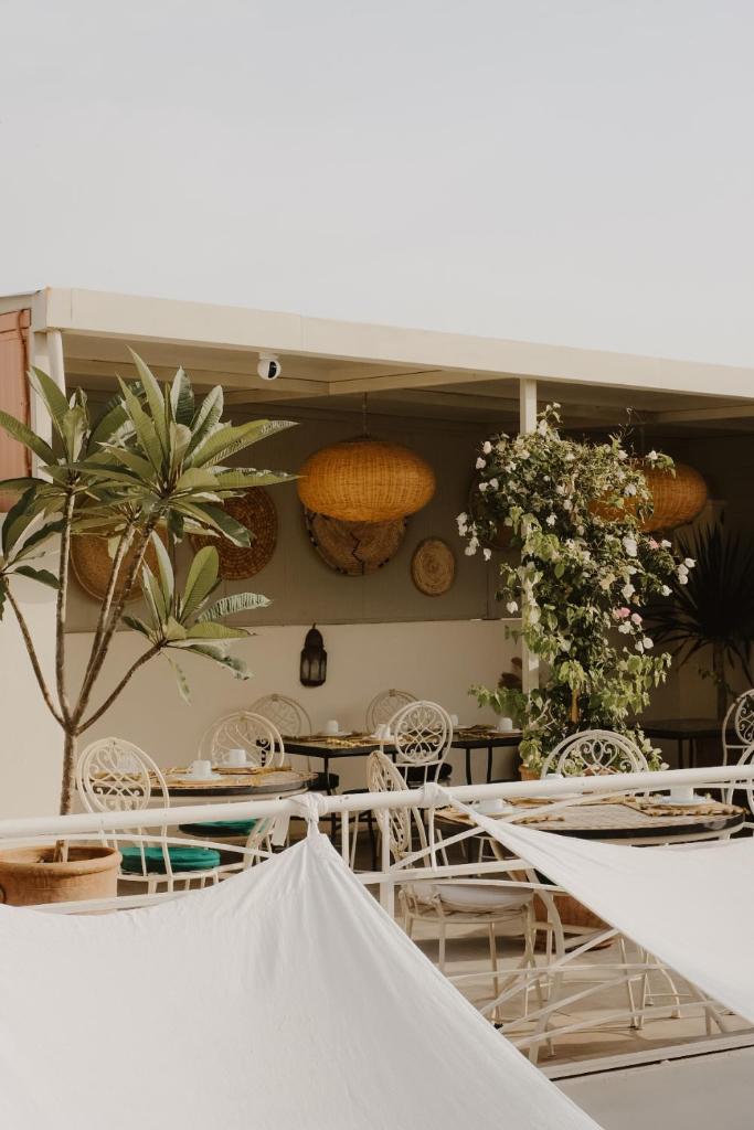 une salle à manger avec tables, chaises et plantes dans l'établissement Riad Dar Blanche & Spa, à Marrakech