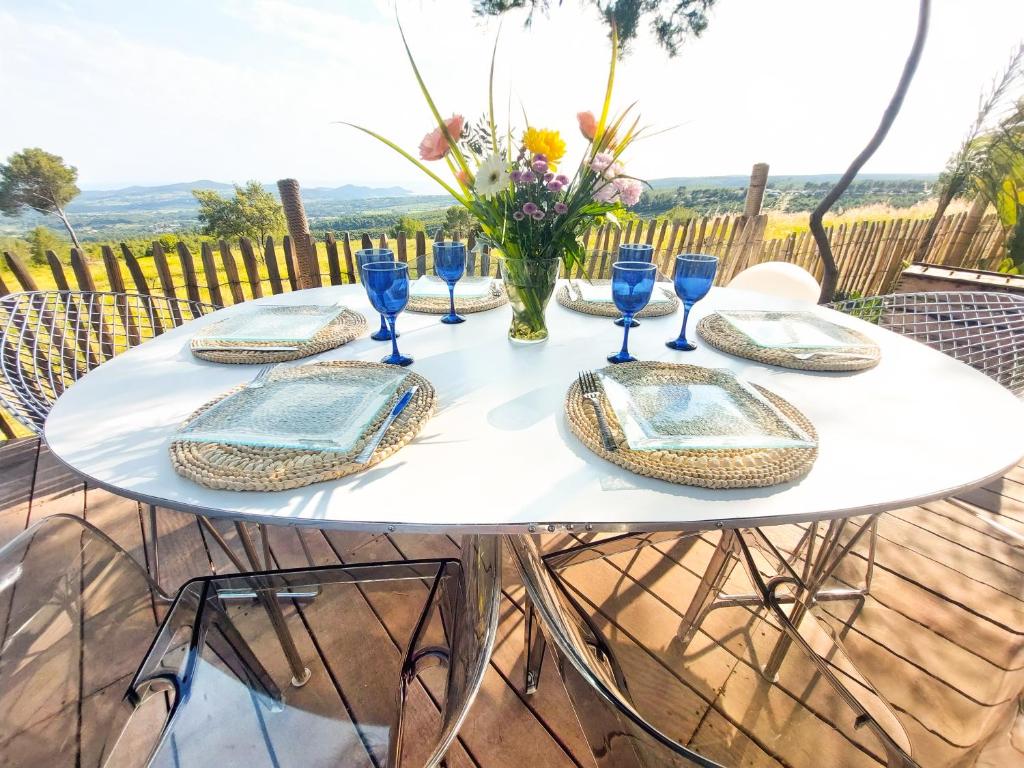 une table blanche avec des assiettes et des lunettes bleues dans l'établissement Chalet, Oasis et vue mer,proxi circuit Paul Ricard, au Castellet