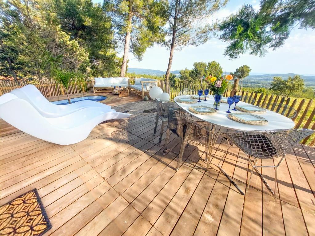 une terrasse en bois avec une table et des chaises. dans l'établissement Chalet, Oasis et vue mer,proxi circuit Paul Ricard, au Castellet