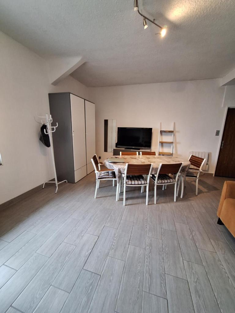 un salon avec une table, des chaises et une télévision dans l'établissement Grand Studio rénové, tout confort, belles prestations - Résidence du Bois de l'Ours, aux Rousses
