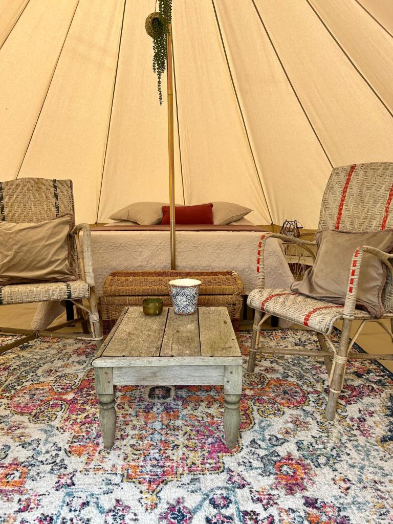 une tente avec un lit, deux chaises et une table dans l'établissement Chambre au jardin Tente de charme, à Éguzon-Chantôme