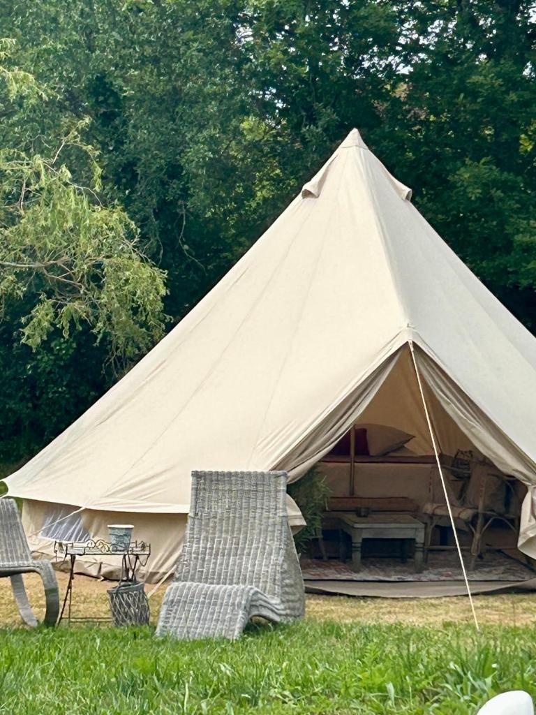 une grande tente avec 2 chaises dans l'herbe dans l'établissement Chambre au jardin Tente de charme, à Éguzon-Chantôme