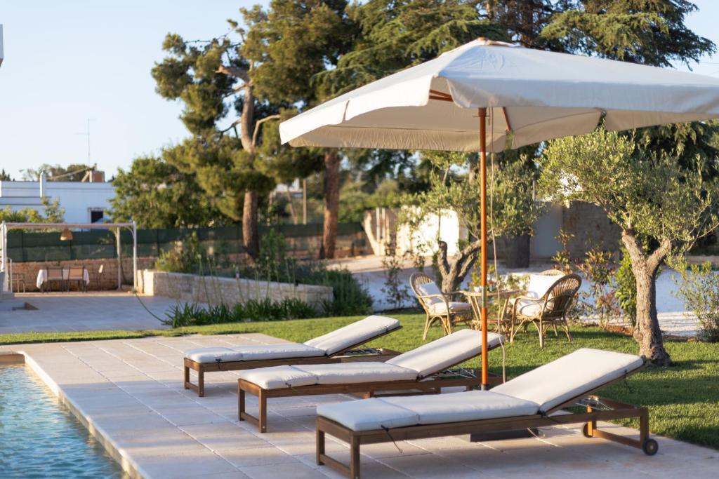 - un ensemble de chaises longues et d'un parasol à côté de la piscine dans l'établissement Bianca Balistris, à Polignano a Mare