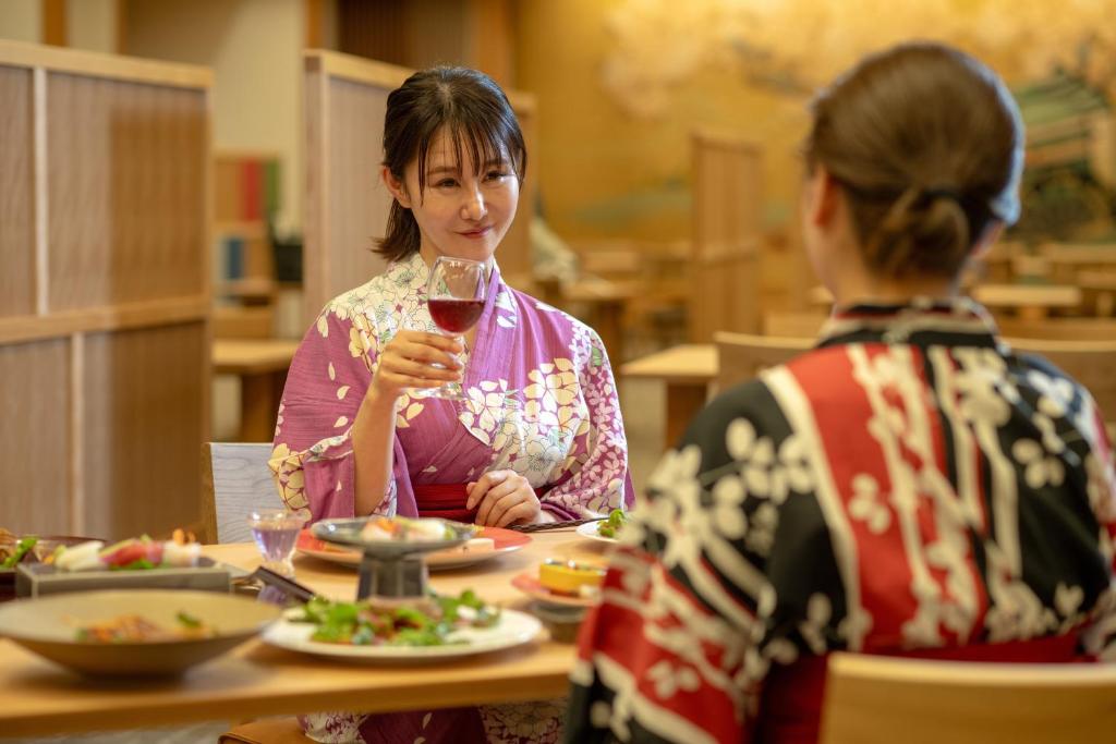 deux femmes assises à une table avec un verre de vin dans l'établissement Eirakukan, à Koriyama