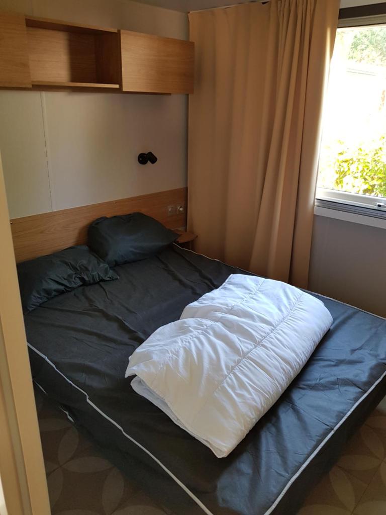 un lit dans une chambre avec une fenêtre dans l'établissement Mobil home Aventura 8 places, à Gastes