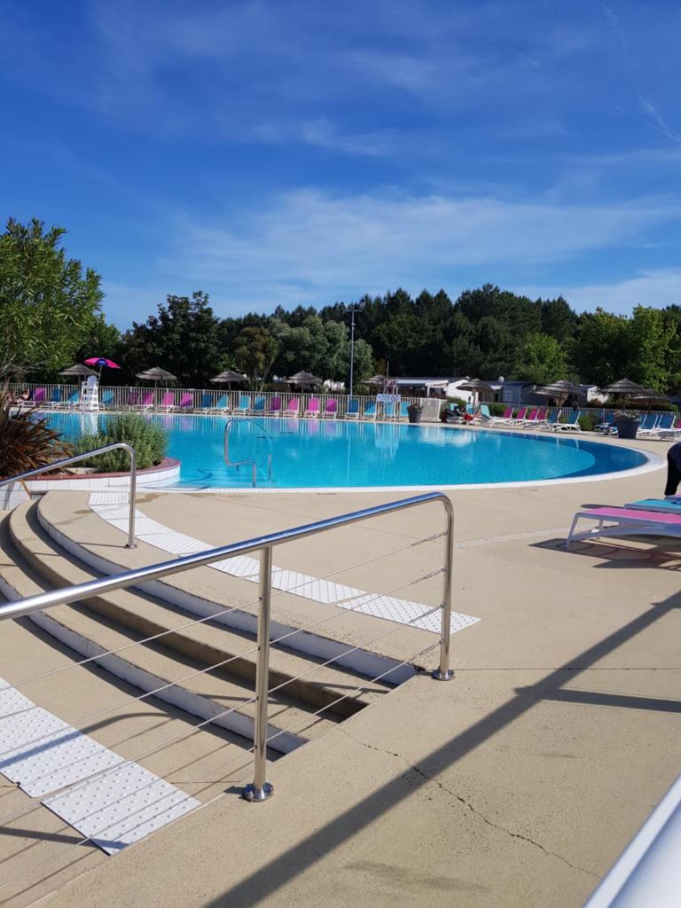 une grande piscine d'eau bleue et des escaliers. dans l'établissement Mobil home Aventura 8 places, à Gastes