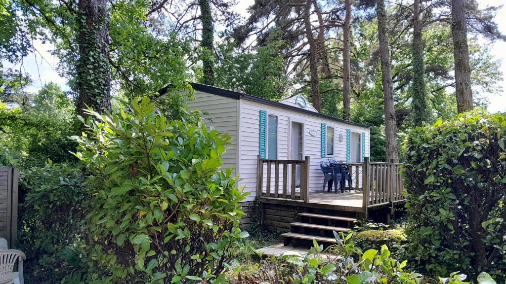 une petite maison blanche avec des volets bleus sur un porche dans l'établissement Camping 46 Rainettes, à Goujounac
