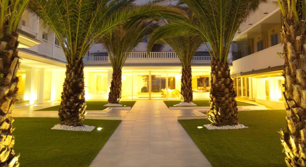 une rangée de palmiers devant un bâtiment dans l'établissement Altamarea Residence & Family Hotel, à Cervia