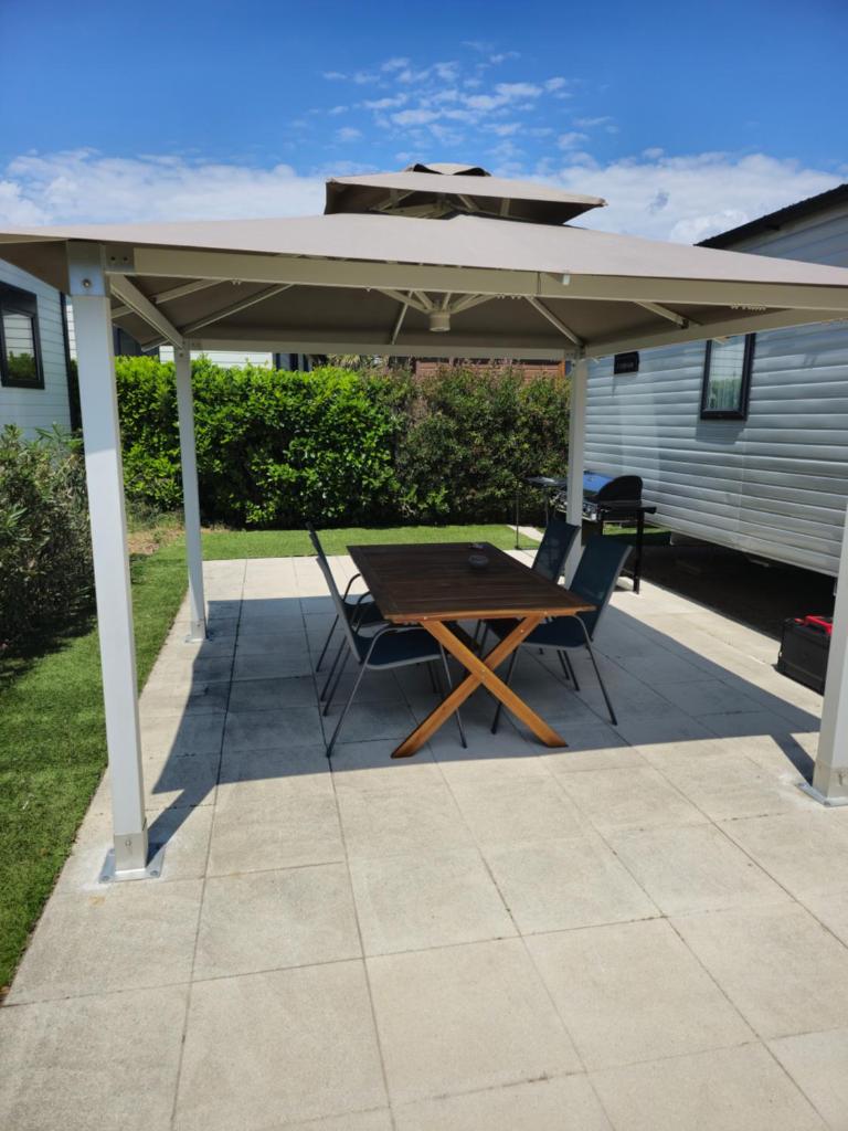 un patio avec une table et des chaises sous un pavillon dans l'établissement Premium Mobilhome Grimaud, à Grimaud