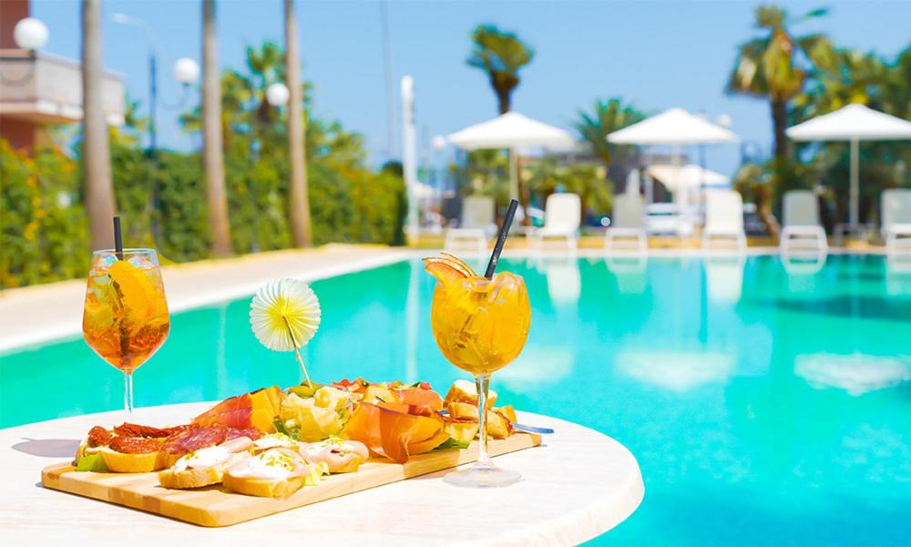 une assiette de nourriture sur une table à côté d'une piscine dans l'établissement Residence La Villa, à Tortoreto Lido