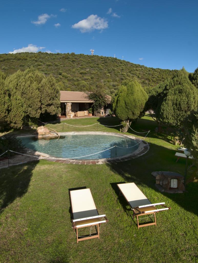 2 chaises longues dans l'herbe près d'une piscine dans l'établissement Hotel Spartivento, à Chia