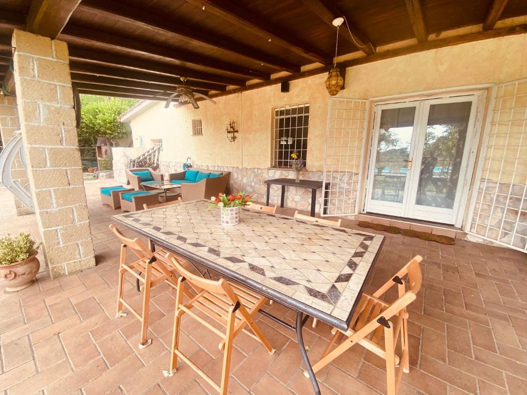 un patio avec une table, des chaises et une cheminée dans l'établissement Splendida villa con piscina, à Vignanello