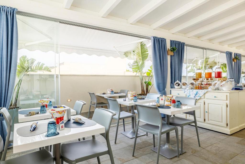 une salle à manger avec des tables et des chaises blanches dans l'établissement Hotel Soffio D'Estate, à San Vito Lo Capo