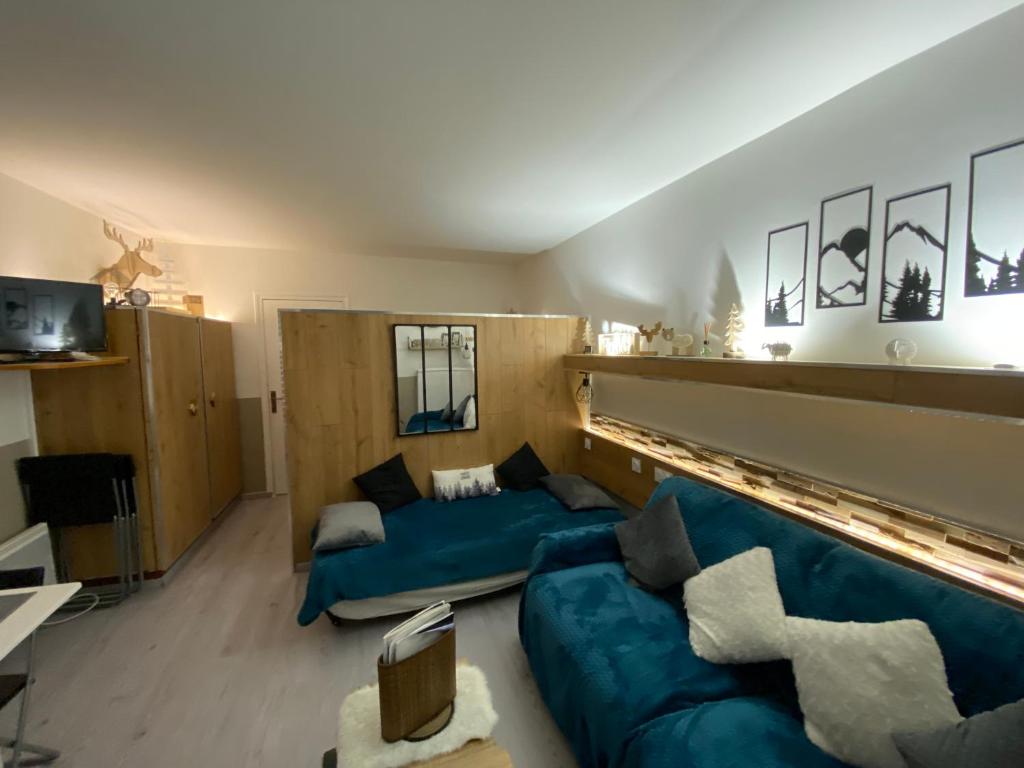 un salon avec un canapé bleu et une télévision dans l'établissement STUDIO AUX PIEDS DES PISTES, à Saint-Étienne-en-Dévoluy