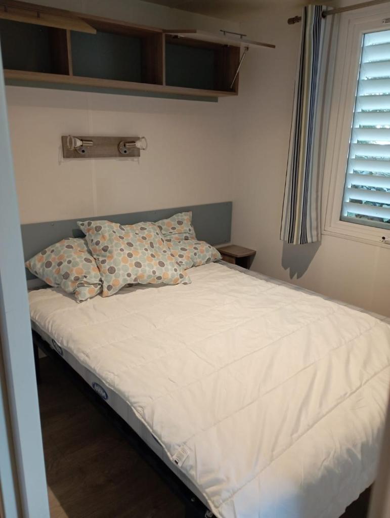 - un lit avec deux oreillers dans une chambre dotée d'une fenêtre dans l'établissement Camping Siblu Mobilhome 2 chambres, à Lège-Cap-Ferret
