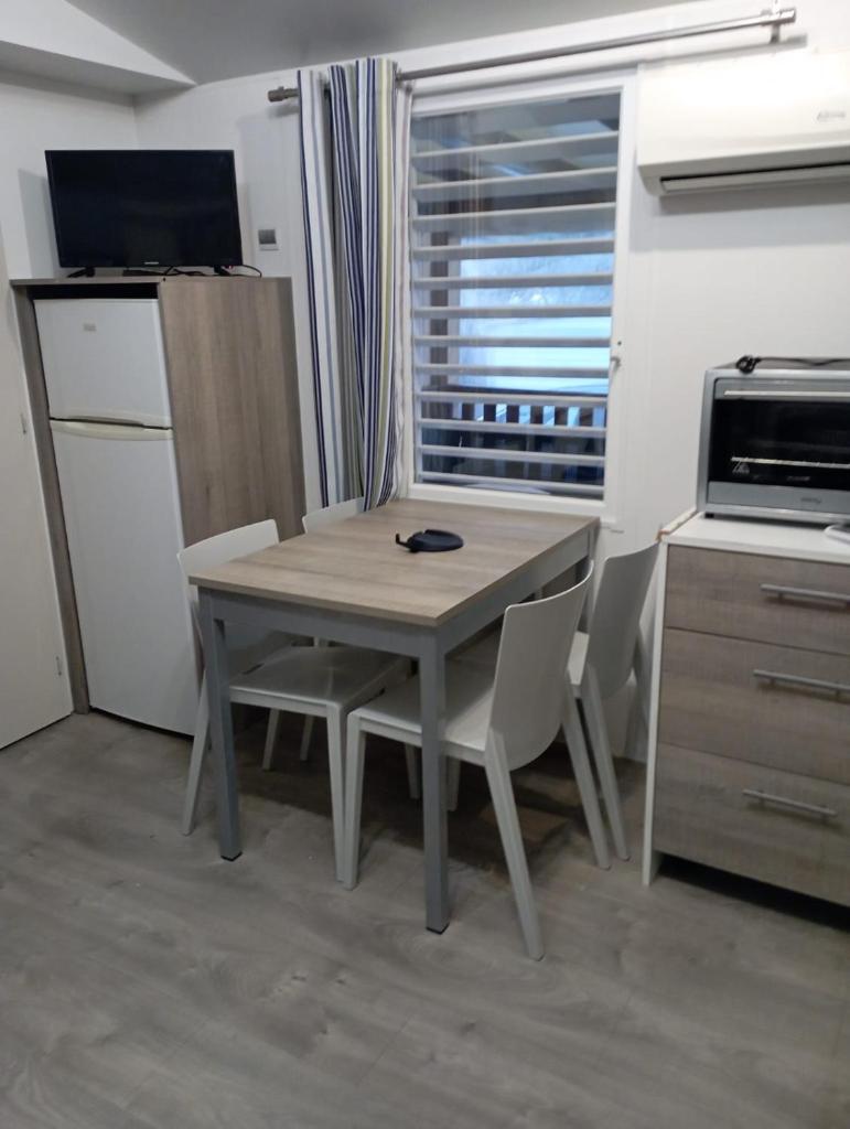 une table et des chaises dans une cuisine avec une fenêtre dans l'établissement Camping Siblu Mobilhome 2 chambres, à Lège-Cap-Ferret