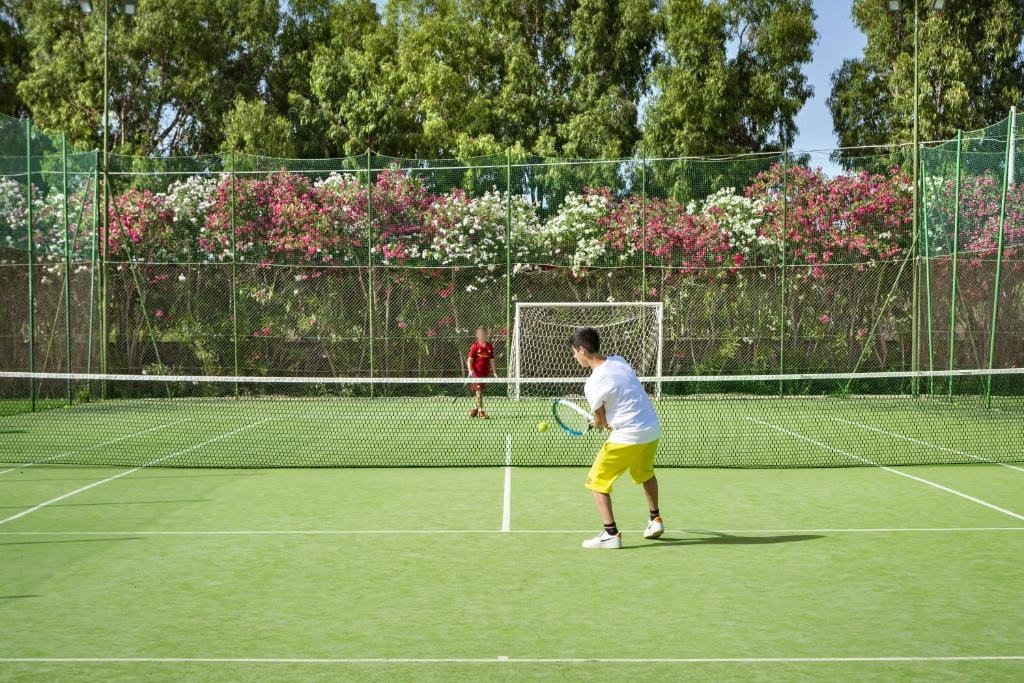un homme debout sur un court de tennis tenant une raquette dans l'établissement Sentido Orosei Beach, à Orosei