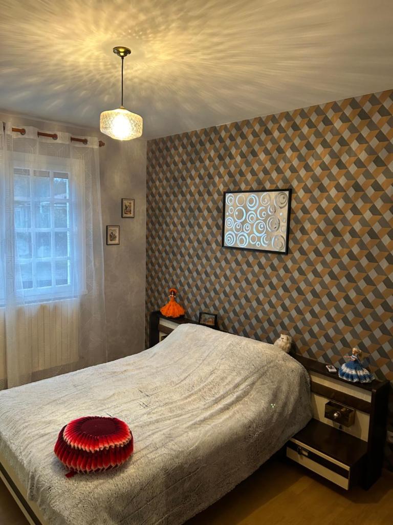une chambre avec un lit avec un oreiller rouge dessus dans l'établissement Gîte LA MAISON ROSE, à Lannemezan