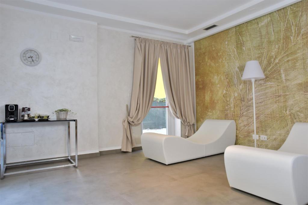 un salon avec des meubles blancs et une fenêtre dans l'établissement Hotel Vienna Ostenda e Ristorante il Danubio, à Rimini