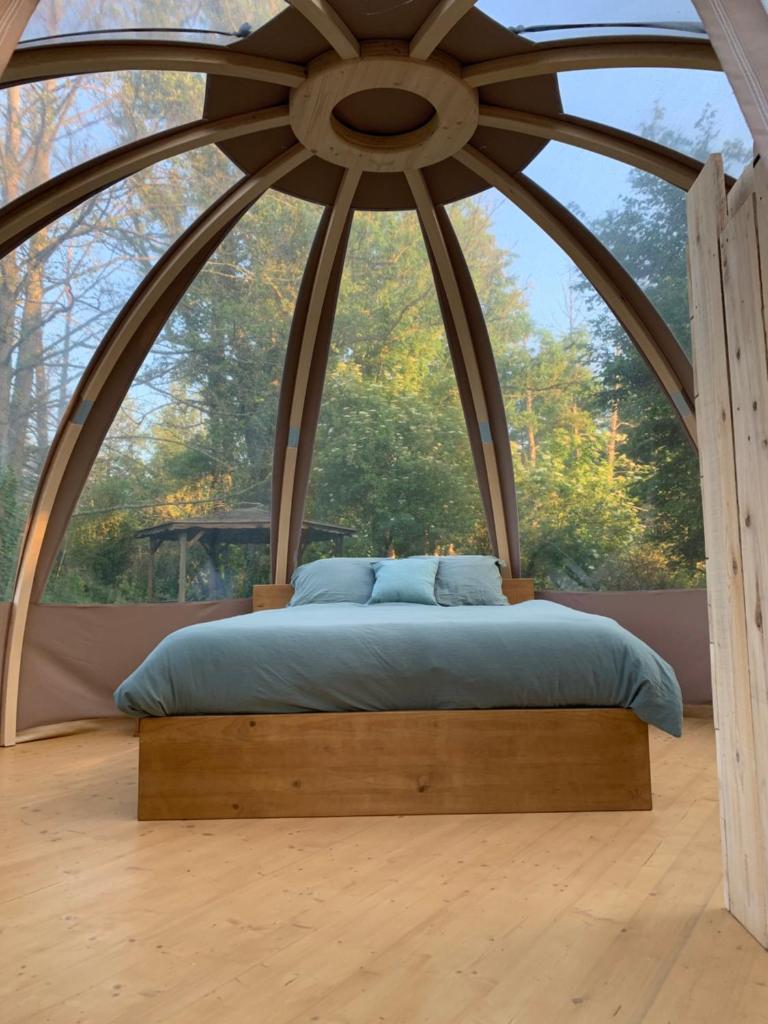 un lit dans une chambre avec une grande fenêtre dans l'établissement Bulle insolite Wigwam, à Aulnay-sur-Iton