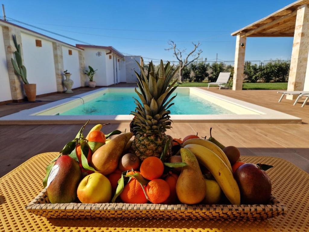 - une corbeille de fruits sur une table à côté de la piscine dans l'établissement Casa Valerio, à Conversano