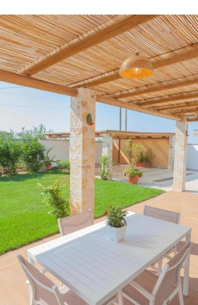 une table et des chaises blanches sous une pergola en bois dans l'établissement Casa Valerio, à Conversano