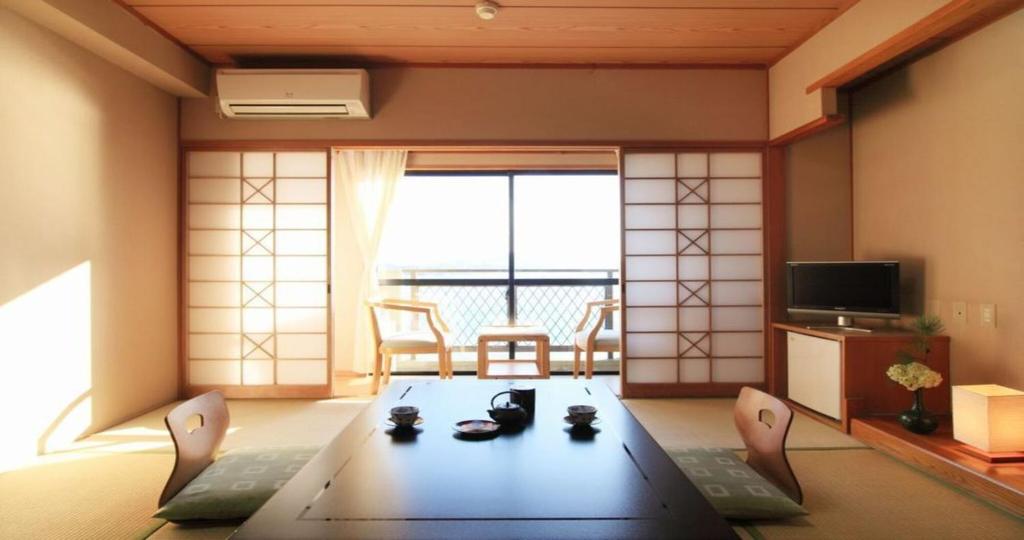 un salon avec une table et une grande fenêtre dans l'établissement Komatsuya Nagisakan, à Kami Amakusa