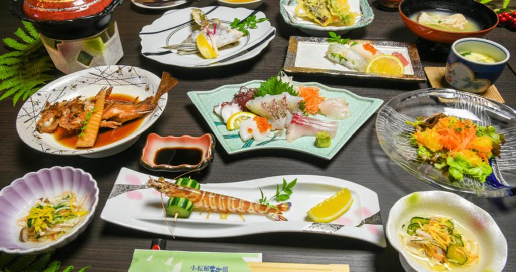 une table avec de nombreuses assiettes de nourriture dessus dans l'établissement Komatsuya Nagisakan, à Kami Amakusa