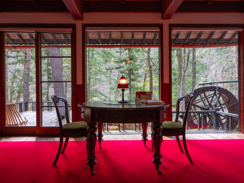 une chambre avec une table et des chaises sur un tapis rouge dans l'établissement Wanosato, à Takayama
