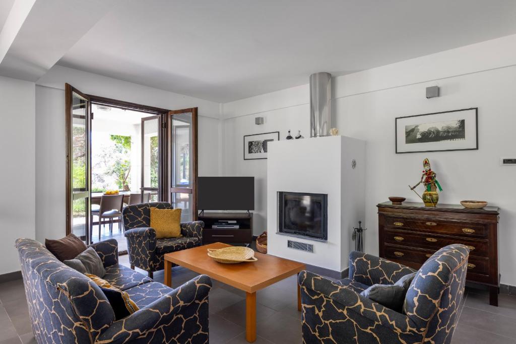 un salon avec des chaises, une table et une télévision dans l'établissement Villa Angelica by Wonderful Italy, à Castellammare del Golfo