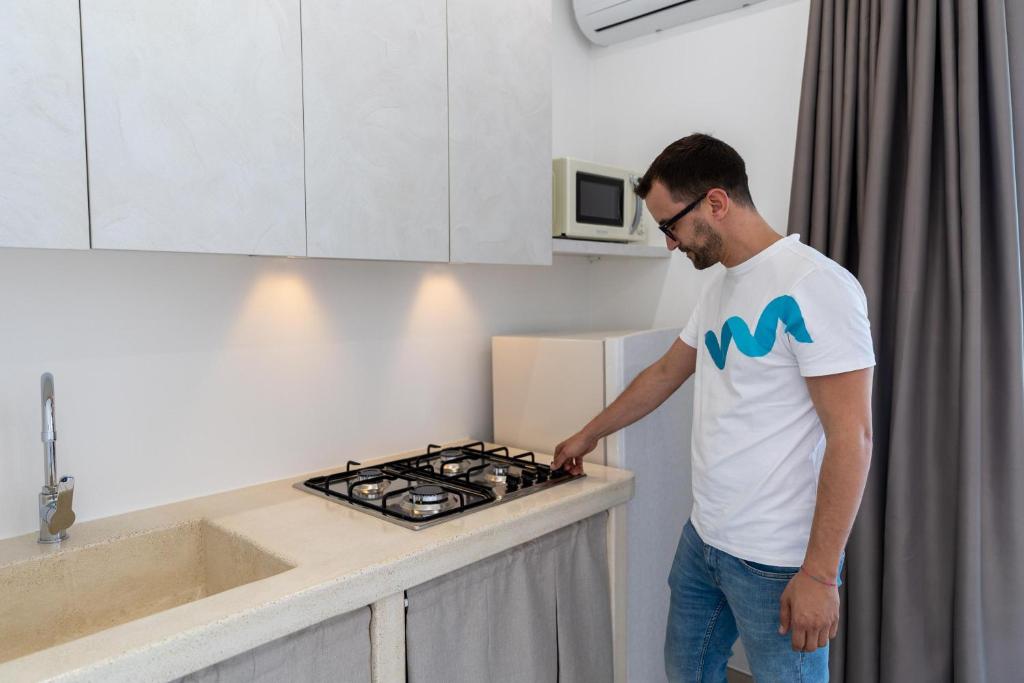 un homme debout dans une cuisine donnant sur une cuisinière dans l'établissement Tenuta Aspri, à Carovigno